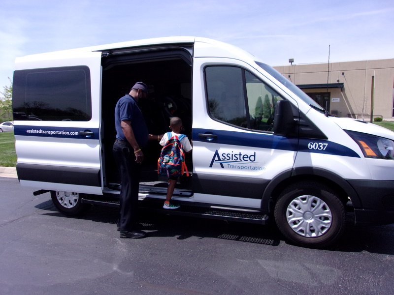 Assisted Driver helps a young child board a van for school transport.